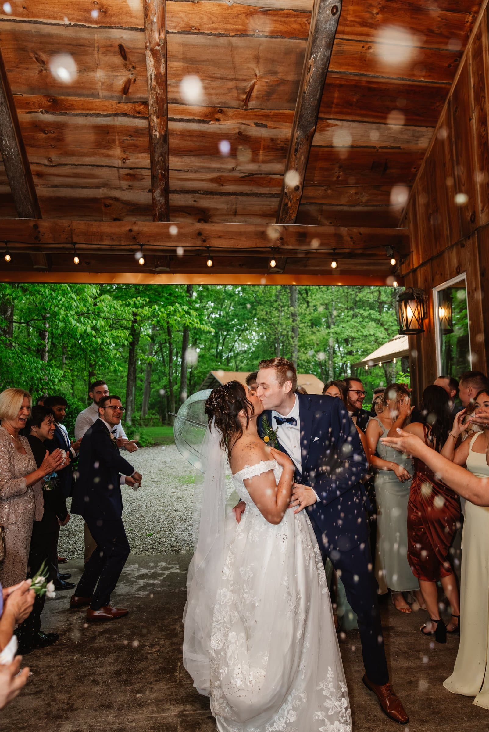 Newlyweds kissing during their send-off as guests cheer and bubbles fill the air