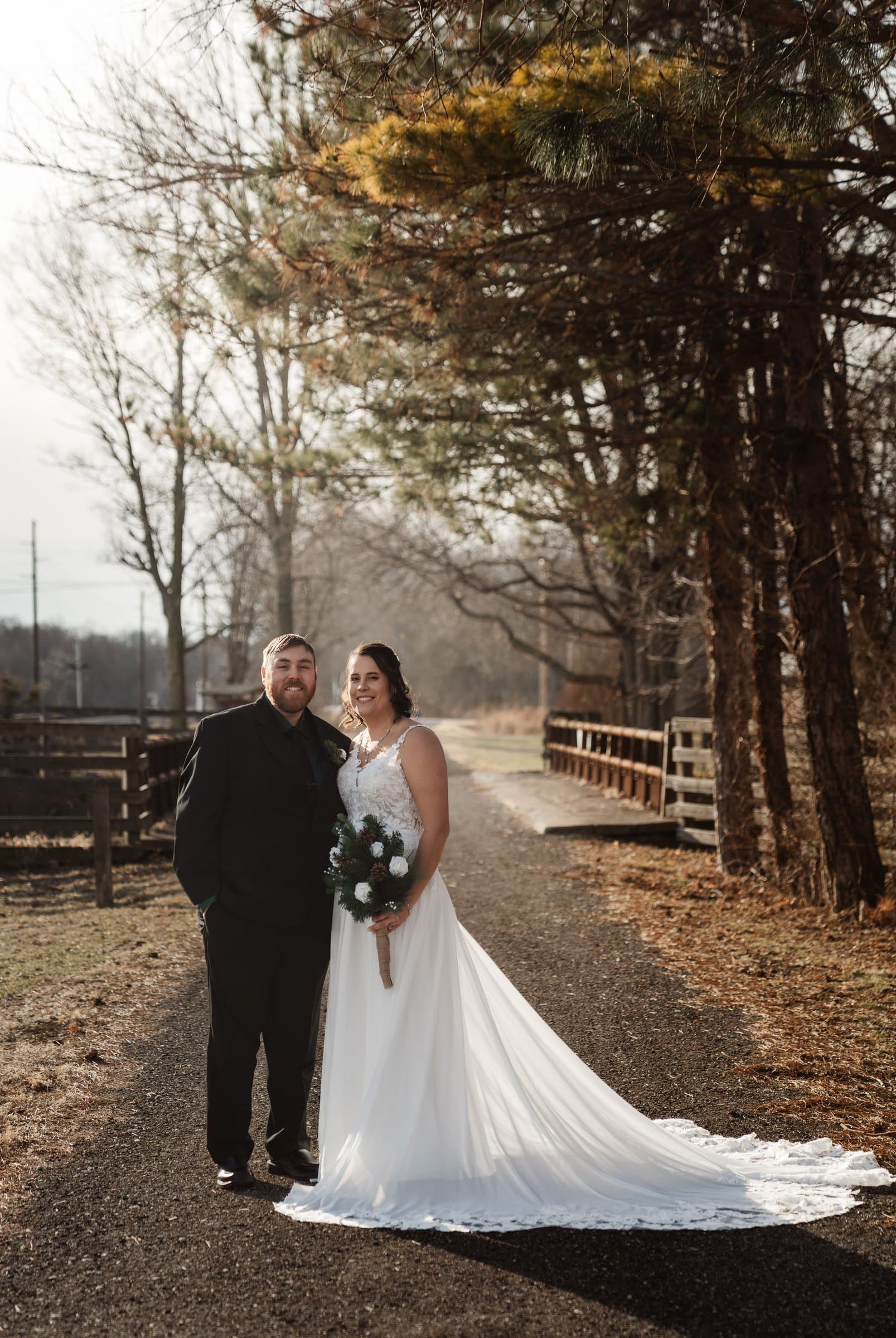 Bride and groom on a gravel path lined with bare winter trees