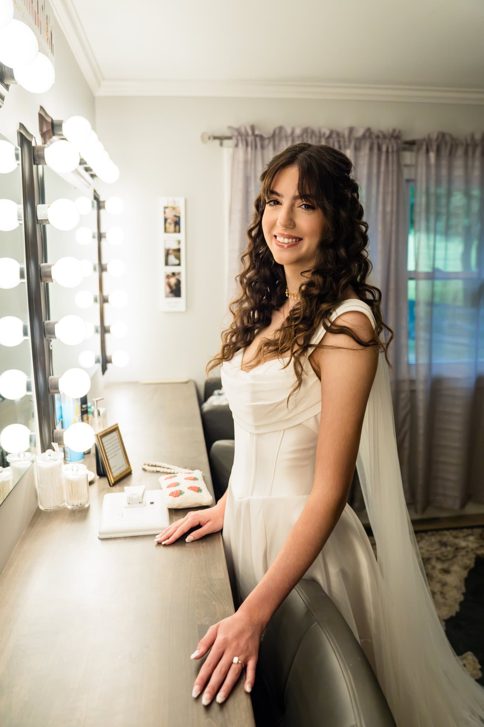 Bride at a lighted vanity table in her getting-ready room